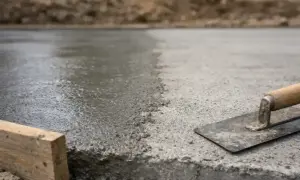 Świeżo wylany beton z kielnią i drewnianym klockiem.
