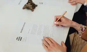 Kobieta podpisuje dokument "DIVORCE DECREE". Wniosek o rozwód można pobrać online.