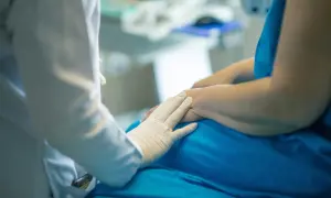 Lekarz w białej rękawiczce delikatnie dotyka dłoni pacjenta. Rozmowa o tym, porfiria co to, trwa w tle.
