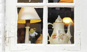 Finestra con oggetti in stile rétro: una lampada, una statuetta e una teiera decorata.