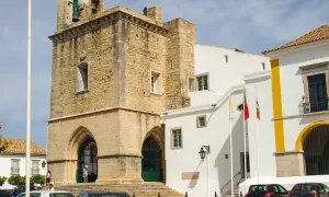 Historisches Gebäude mit Glockenturm in der faro portugal altstadt. Weiße Gebäude mit gelben Akzenten und portugiesische Flaggen.
