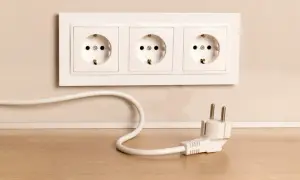 Biały kabel biegnie od gniazdka do wtyczki. Dowiedz się, jak zamaskować kable na ścianie, by uniknąć bałaganu.