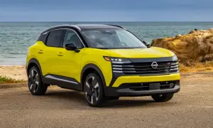 Żółty Nissan Kicks z czarnym dachem stoi na plaży przy spokojnym morzu.