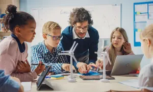 Maestro explica a niños modelos de molinos de viento, un ejemplo de pensamiento computacional aplicado a la energía.