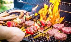 Brochettes de viande et légumes, saucisses et steaks sur un barbecue au barbecue, avec des flammes vives.