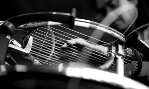 Mano che regola la tensione delle corde di una racchetta da tennis, un dettaglio cruciale per la performance.