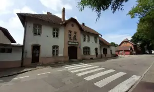 Dworzec PKP Łeba, zabytkowy budynek z cegły i jasnego tynku, z charakterystycznym napisem nad wejściem. Przed nim pasy dla pieszych.