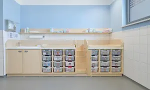 Praktische Elternecke Kita gestalten: Wickeltische, Waschbecken und viele durchsichtige Schubladen für Windeln und Kleidung.