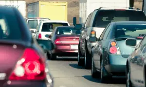 Korki na drodze, samochody stoją w rzędzie. Jeden z kierowców próbuje wyprzedzanie, ale ruch jest bardzo wolny.