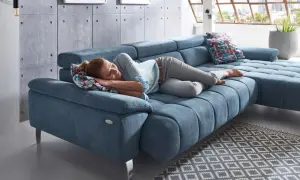 Kobieta śpi na niebieskiej sofie, która jest tak wygodna, że można zapomnieć, czym się różni sofa od kanapy.
