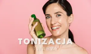 Uśmiechnięta kobieta trzyma butelkę z zielonym płynem, prezentując swój zdrowy wygląd po zastosowaniu toniku do twarzy.