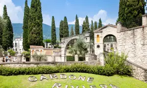 Giardini del Vittoriale, con cipressi svettanti, architetture in pietra e il nome "Gardone Riviera" sull'erba. Ecco cosa vedere al Vittoriale.
