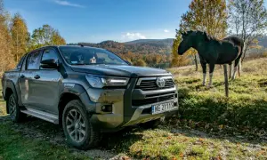 Toyota Hilux GR Sport na tle jesiennych wzgórz, obok stoi koń.