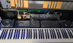 Wnętrze keyboardu podczas naprawy. Widoczne głośniki, płytki drukowane, kable i klawisze.