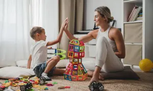 Mama i syn budują wieżę z klocków, ciesząc się wspólnymi zabawami na 3 osoby w domu.