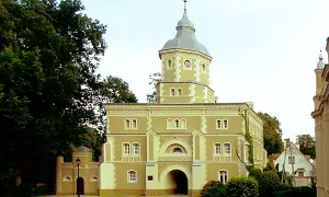 Pałac w Golejewku, z charakterystyczną wieżą i bramą wjazdową, otoczony zielenią.