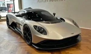 Srebrny Aston Martin na drewnianej podłodze. Zastanawiasz się nad aston martin cena?