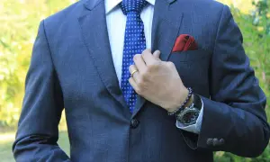 Mann im grauen Anzug mit blauer Krawatte, die perfekt zu seinem blauen Anzug passt. Rotes Einstecktuch.