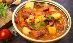 Gęsta zupa gulaszowa z ziemniakami, mięsem i kiełbasą, posypana natką pietruszki.