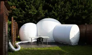Une bulle gonflable blanche, prête pour une nuit insolite en Île-de-France, est installée dans un jardin verdoyant.