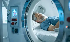 Mężczyzna śpi w komorze hiperbarycznej, czekając na pozytywne efekty terapii tlenowej.