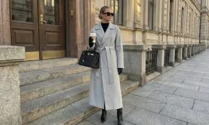 Elegancki szary płaszcz z paskiem, połączony z czarnymi kozakami i torebką, tworzy stylowy look.