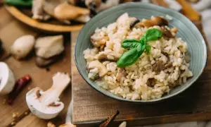 Kremowe risotto z grzybami, ozdobione listkiem bazylii. Idealny ryż do risotto, który wchłonął smak leśnych skarbów.