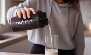 Frau gießt pflanzliches Protein aus einem Shaker in ein Glas. Informiere dich über mögliche proteinpulver nebenwirkungen.