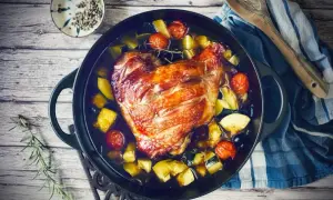 Knusprige putenoberkeule im Bräter mit Gemüse, Tomaten und Kräutern.