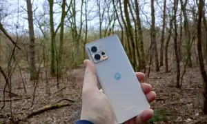 Dłoń trzyma srebrny smartfon Motorola G13 na tle lasu. Sprawdź motorola g13 dane techniczne, by poznać jego możliwości.