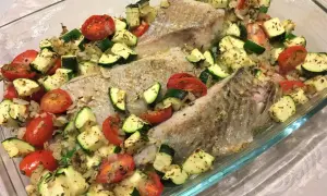 Filet de lieu noir rôti avec tomates cerises et courgettes coupées en dés, assaisonné d'herbes.