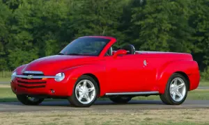 Czerwony Chevrolet SSR z otwartym dachem, gotowy na letnią przejażdżkę pośród zieleni.