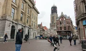 Menschen spazieren durch die Kopfsteinpflasterstraßen der utrecht altstadt, vorbei an historischen Gebäuden und dem Domturm.