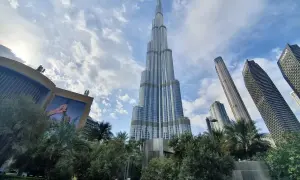 Majestatyczny Burj Khalifa w Dubaju wznosi się ku niebu, otoczony nowoczesnymi wieżowcami i zielenią.