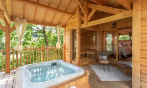 Terrasse en bois avec jacuzzi, sauna et chambre. Une invitation à une nuit insolite au nord, au cœur de la nature.