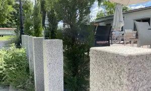 Granit-Palisaden setzen einen eleganten Akzent vor grüner Bepflanzung und laden zum Verweilen auf der Terrasse ein.