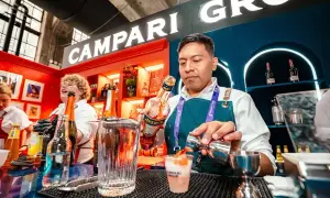 Barman przygotowuje drinka z Aperol. W tle widać logo Campari Group.