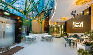 Nowoczesna strefa gastronomiczna "food hall Krzywy Domek Sopot" z zielonymi meblami i oświetleniem.