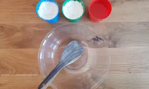 Zutaten für das Oobleck-Rezept: Mehl in blauen und grünen Bechern, Wasser im roten Becher und eine Schüssel mit Löffel.