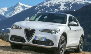 Białe Alfa Romeo Stelvio na tle ośnieżonych gór. Wiele pozytywnych alfa romeo stelvio opinie potwierdza jego wszechstronność.