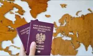 Dłoń trzyma dwa polskie paszporty na tle drewnianej mapy Europy. Czas na podróż!