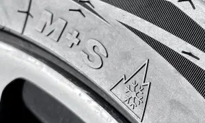 Nahaufnahme eines Reifens mit "M+S"-Kennzeichnung und dem Schneeflockensymbol, das auf Winterreifen hinweist.