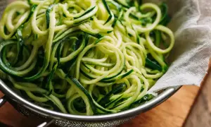 Frische Zucchini Spaghetti in einem Sieb, bereit für eine leichte Mahlzeit.