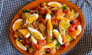 Deliciosa ensalada de patatas de verano con huevos duros, tomates, pimientos y aceitunas.