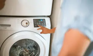 Mano che seleziona "Warm" sul pannello di una lavatrice, per capire quanto consuma una lavatrice a 40 gradi.