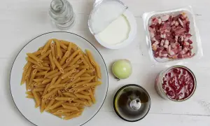 Penne, boczek, śmietana, cebula, oliwa, pomidory z puszki na białym tle.