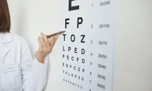 Okulista wskazuje na tablicę Snellena. Czy astygmatyzm może wpłynąć na orzeczenie o niepełnosprawności?