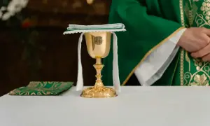 Złoty kielich i zielona stuła kapłana podczas post eucharystyczny.