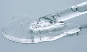Kropla przejrzystego serum z pęcherzykami powietrza, zawierającego peptydy i ceramidy, spływa z pipety.