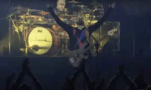 Wokalista Riverside z uniesionymi rękami, basista na scenie, perkusista w tle. Koncertowa atmosfera, publiczność wiwatuje.